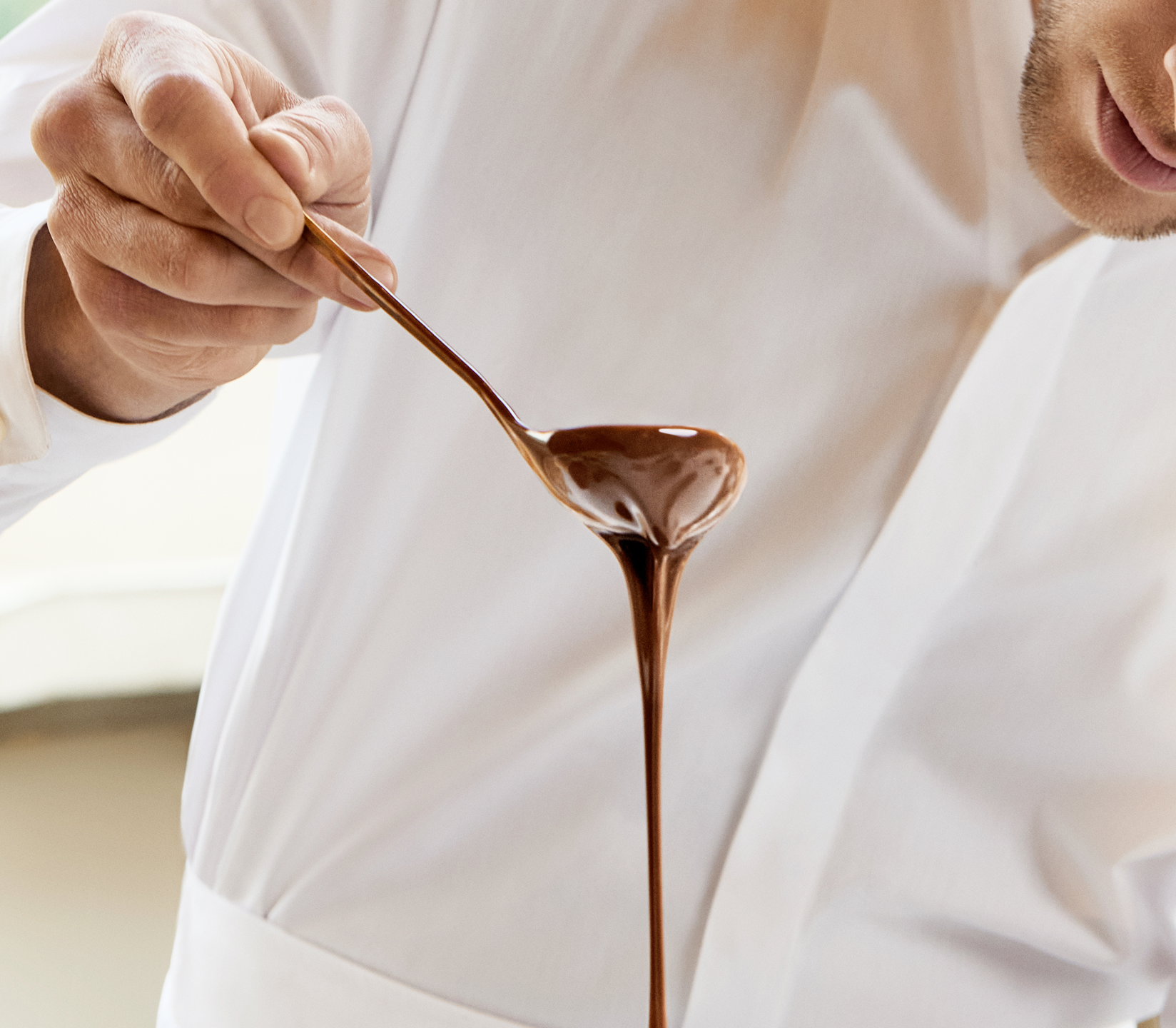 A chef pouring chocolate sauce from a ladle